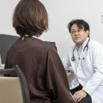 診察室で患者様に説明を行う院長鈴木